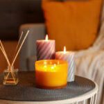 Burning candles and reed air freshener on table indoors. Cosy atmosphere